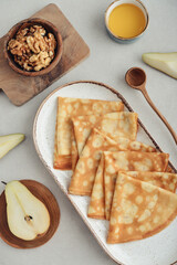 Thin pancakes, homemade crepes on a plate with pear