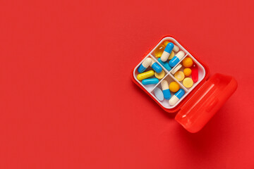 Container with different pills on red background