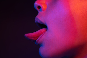 Tongue lick. Sexy woman mouth with tongue sticking out. Sexy tongue. Tongue out. Neon Light, night sexy scene. - obrazy, fototapety, plakaty