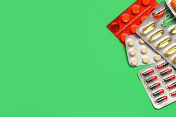 Blister packs with different pills on green background