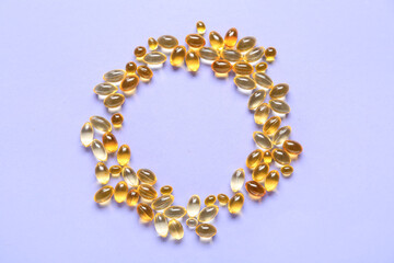 Frame made of different fish oil capsules on color background