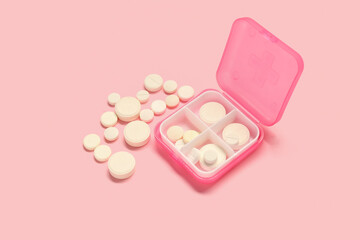 Container with white pills on pink background