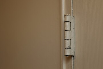 Close-up of a painted door hinge on a wooden door frame