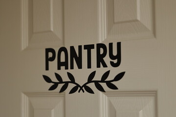A close-up of a pantry door with the word 'PANTRY' labeled in bold, black lettering and a...