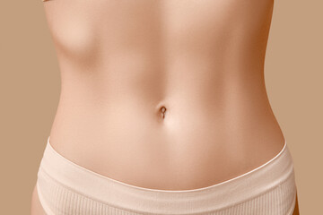 Young woman with flat belly on beige background, closeup. Plastic surgery concept - obrazy, fototapety, plakaty