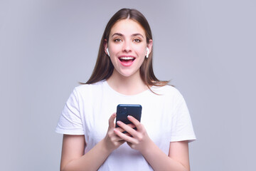 Fototapeta premium Young woman using phone device gadget app isolated over studio background. Girl holding a smartphone, chatting by mobile phone. Girl using phone, studio portrait. Woman makes telephone call on phone.