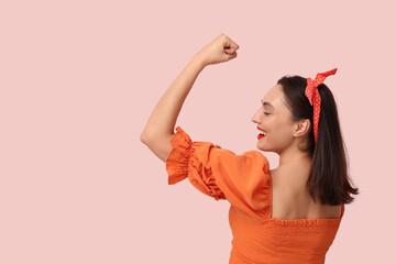 Beautiful happy pin-up woman showing her muscles on pink background