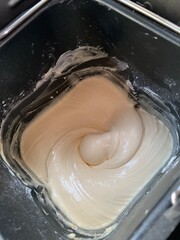 Making buttercream frosting for decorating a vanilla cake, Closeup of electric mixer with whipped smooth dough for cake. Batter being whipped. Mixing white dough in bowl with motor mixer baking cake