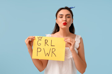 Beautiful young pin-up woman holding paper with text GRL PWR on light blue background