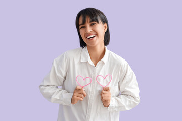 Beautiful young woman with decorative hearts on lilac background. Valentine's day celebration