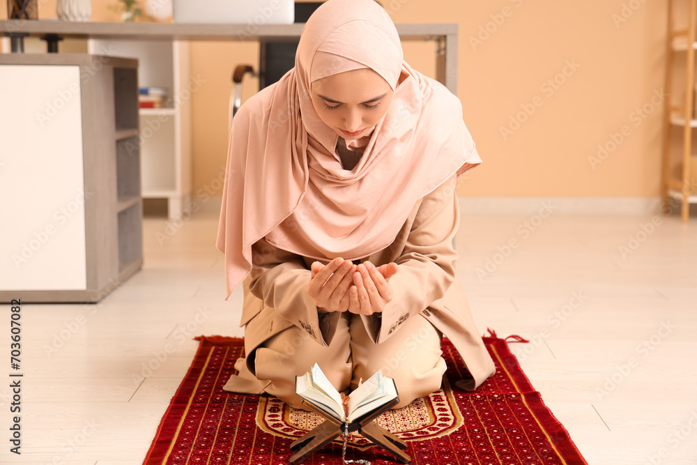 Wall mural Young Muslim woman with Koran praying in office