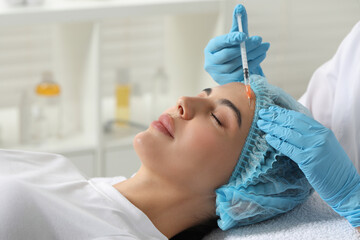 Doctor giving facial injection to young woman in clinic. Cosmetic surgery