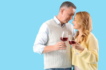 Mature couple with glasses of wine on blue background