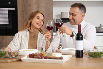 Mature couple with glasses of wine having dinner in kitchen