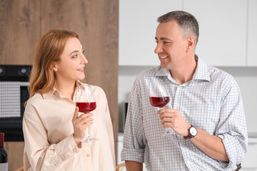Mature couple with glasses of wine in kitchen