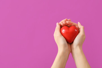 Female hands with heart on purple background. Valentine's Day celebration