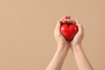 Female hands with heart on brown background. Valentine's Day celebration