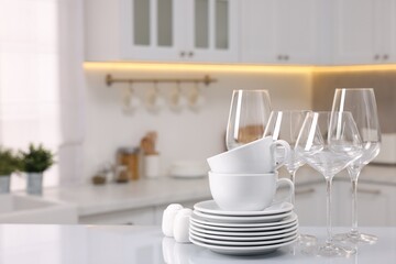 Set of clean dishware and glasses on table in kitchen, space for text