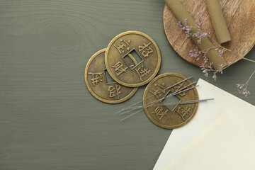 Acupuncture needles, moxa sticks and antique Chinese coins on grey wooden table, flat lay. Space...