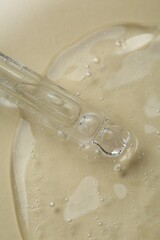 Pipette with cosmetic serum on beige background, above view