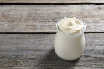 Obraz na płótnie Canvas Fresh mayonnaise sauce in glass jar on wooden table, space for text
