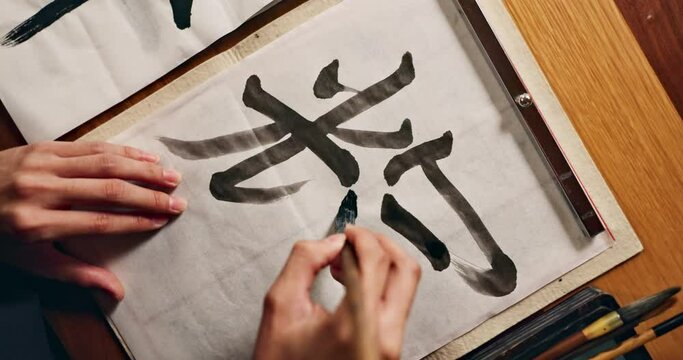 Hands writing, brush and Asian font for art and script, calligraphy with closeup of alphabet. Japanese, creative person or top view of vintage tools, paintbrush and stroke with traditional stationery