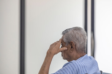 Elderly male patient waiting to see doctor with worry putting hand on his head.