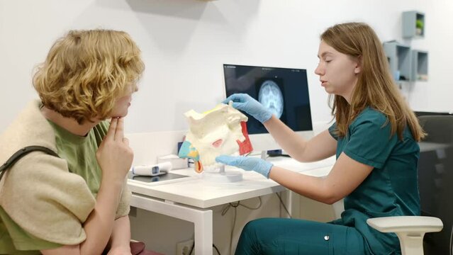 A otolaryngologist doctor explains to a patient about his illness at an appointment. Professional ENT doctor shows the features of a nose and sinus disease. Sinusitis, nasal septum deviation problems
