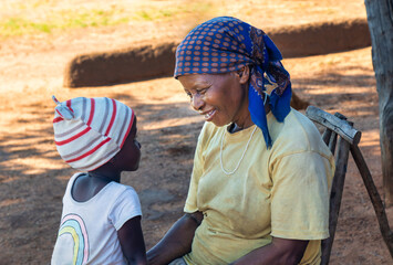 portrait of an village African woman with a child telling stories and listening at sunset, village...