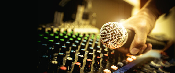 Hand DJ holding microphone on sound mixer in live broadcasting studio producer for sound record...