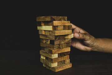 Hand pull wooden block tower stack in pyramid stair step with caution to prevent collapse or crash...