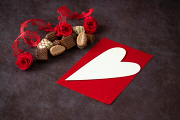 バレンタイン・イメージ　チョコレートと赤いプリザーブドフラワーのバラとハートのリボンとラブレター（茶色の背景）