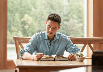 Young man relaxing at home reading a book , bible learning studying  - obrazy, fototapety, plakaty