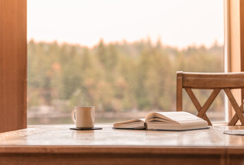 coffee cup on the table reading book by a window with relaxing nature view, concept morning leisure