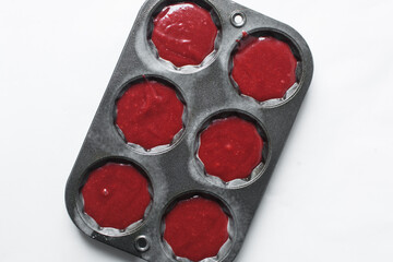 Top view of Red velvet cupcake batter in a fluted muffin tin, process of making valentines cupcakes
