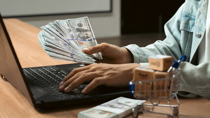 Successful counting money and doing finances while working selling online, working laptop computer from home on wooden floor with postal parcel, Selling online ideas concept, Hands counting money