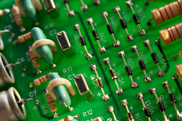 An electronic circuit board made of green fiberglass with many soldered ceramic-painted resistors...