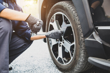 Auto mechanic use wrench to repairing and change car tires. Concept of car care service and maintenance or fix the car leaky or flat tire. - obrazy, fototapety, plakaty