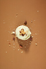 Close-up of almond flakes spread on the surface of a vanilla ice cream on a brown background....