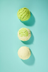 One white ice cream, one green and white ice cream, and one green ice cream are lined up on a...