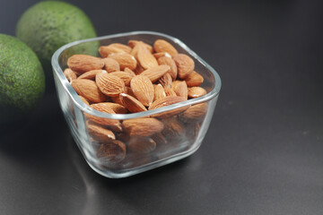 close up of slice of avocado and almond nut on chopping board.