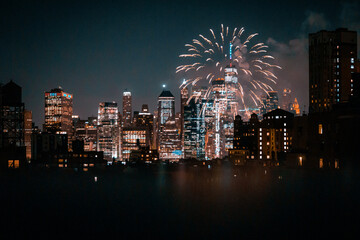 View of financial district Manhattan buildings and lights at night with fireworks at the sky