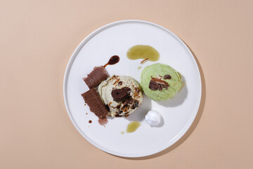 A matcha ice cream and a milk ice cream decorated with chocolate on a white ceramic plate on a pastel background. Perfect layout for food advertising.