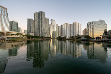Fototapeta na wymiar City of Miami, Florida skyline reflected in calm water of Biscayne Bay at sunrise on clear cloudless December morning.