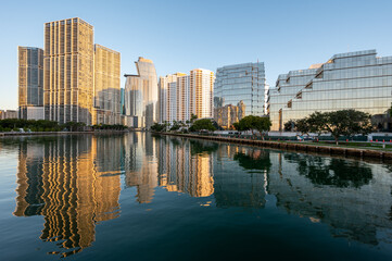Fototapeta na wymiar City of Miami, Florida skyline reflected in calm water of Biscayne Bay at sunrise on clear cloudless December morning.