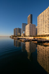 City of Miami, Florida skyline reflected in calm water of Biscayne Bay at sunrise on clear...