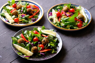Salad de Falafel, consisting of lettuce, cucumber, scallions, cherry tomatoes, olives, sun-dried...