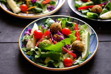 Salad de Falafel, consisting of lettuce, cucumber, scallions, cherry tomatoes, olives, sun-dried tomatoes, and feta. Falafel is a deep-fried ball or patty-shaped fritter made from ground chickpeas. 