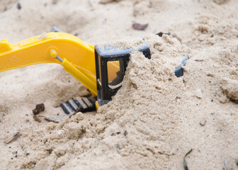 Toy excavator buried in sand on the beach