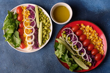 fresh vegetable salad, edamame, sweetcorn, cherry tomatoes, romaine lettuce, sliced cucumber, sliced onions, and purple cabbage. extra virgin olive oil. served on ceramic plate. appetizer. 